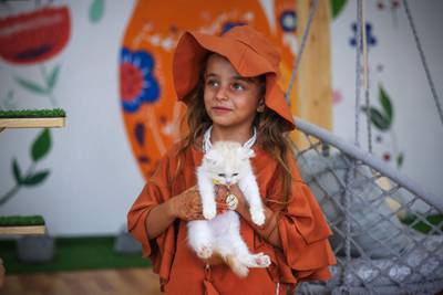 A girl plays with a cat at Meow Cafe. AFP