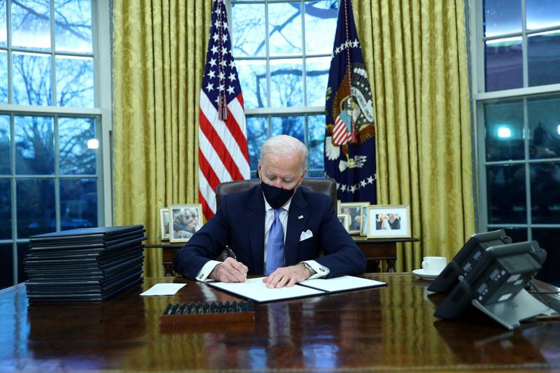 U.S. President Joe Biden signs executive orders in the Oval Office of the White House in Washington, after his inauguration as the 46th President of the United States, U.S., January 20, 2021. REUTERS/Tom Brenner     TPX IMAGES OF THE DAY