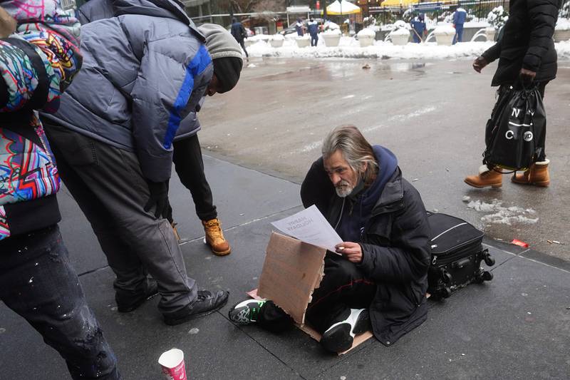 People try and help a man who claims to be homeless the day after a nor'easter storm amid the coronavirus disease (COVID-19) pandemic in the Manhattan borough of New York City, New York, U.S., December 18, 2020. REUTERS/Carlo Allegri