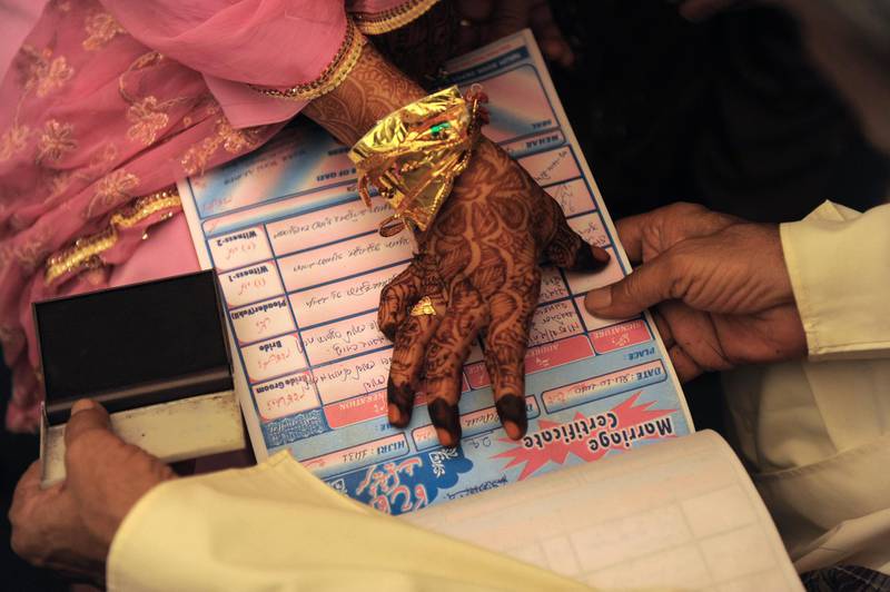 An Indian Muslim bride puts a thumb impression on a Marriage Certificate in the presence of religious leaders and a relative during the "Nikah Kabool Hai"  or "Do You Agree for the Marriage" section of a mass wedding ceremony in Ahmedabad on October 24, 2010. Some 65 Muslim couples participated in a mass wedding ceremony organised by The Fazale Rabbi Samuh Lagna Committee. AFP PHOTO/Sam PANTHAKY / AFP PHOTO / SAM PANTHAKY