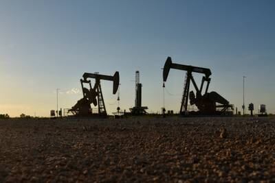 Pump jacks operate in front of a drilling rig in an oil field in Midland, Texas. Reuters