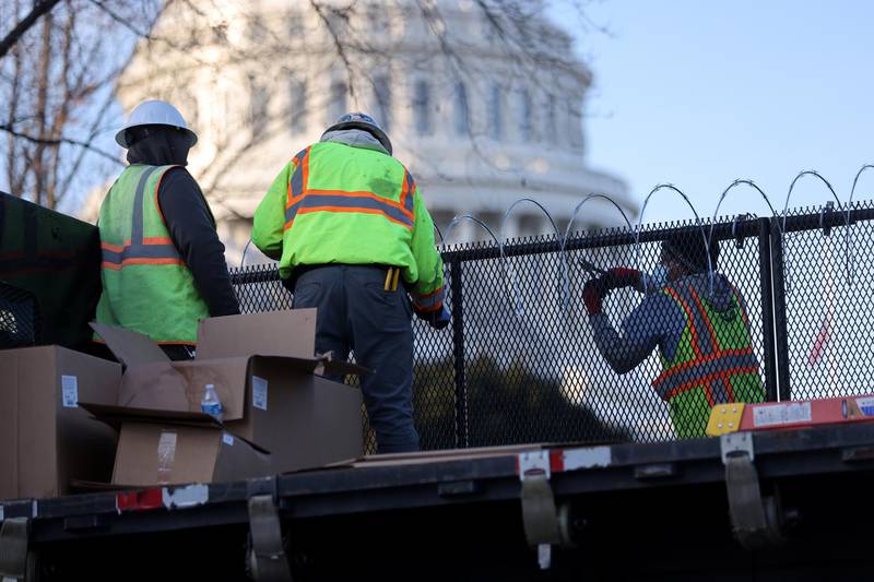 Workers install razor wire atop the unscalable fence surrounding the US Capitol. Reuters
