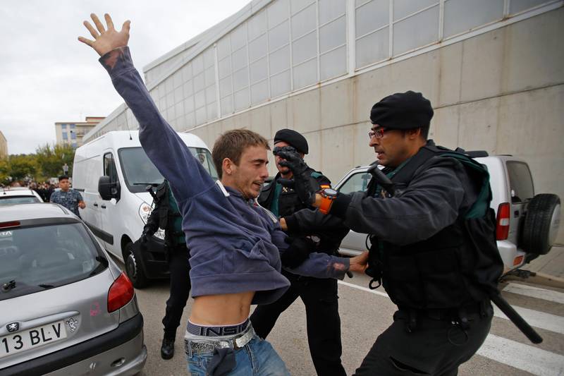 A man is grabbed by civil guards in Sant Julia de Ramis, near Girona, Spain, Sunday, Oct. 1, 2017. Scuffles have erupted as voters protested while dozens of anti-rioting police broke into a polling station where the regional leader was expected to show up for voting on Sunday. (AP Photo/Francisco Seco)