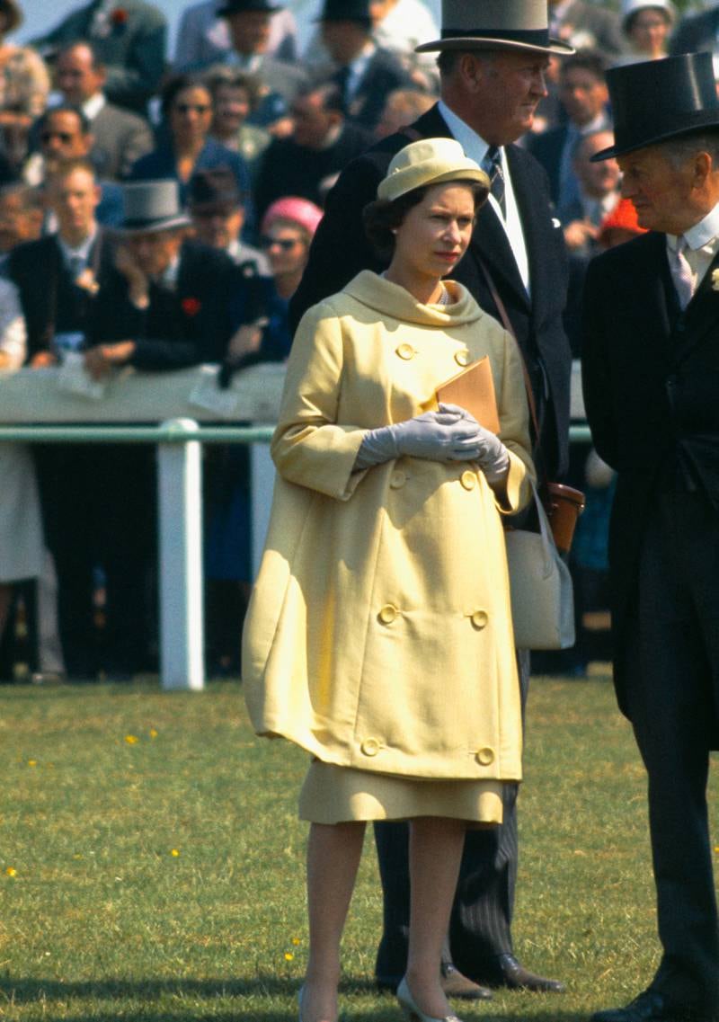 Queen Elizabeth II, wearing yellow, at Epsom Downs Racecourse for the Oaks Stakes, Surrey, 1960. Getty Images