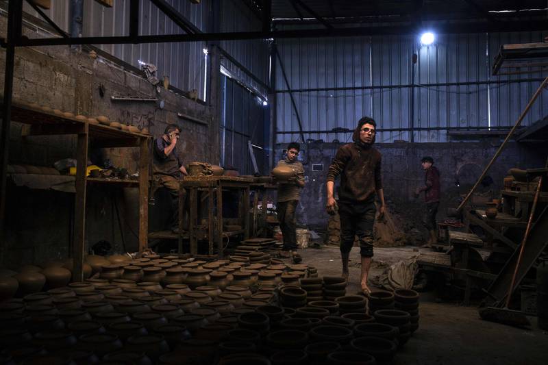 Palestinian potter Sid Atallah, left, and his sons at work at the family workshop in Deir al-Balah in the central Gaza Strip. AFP