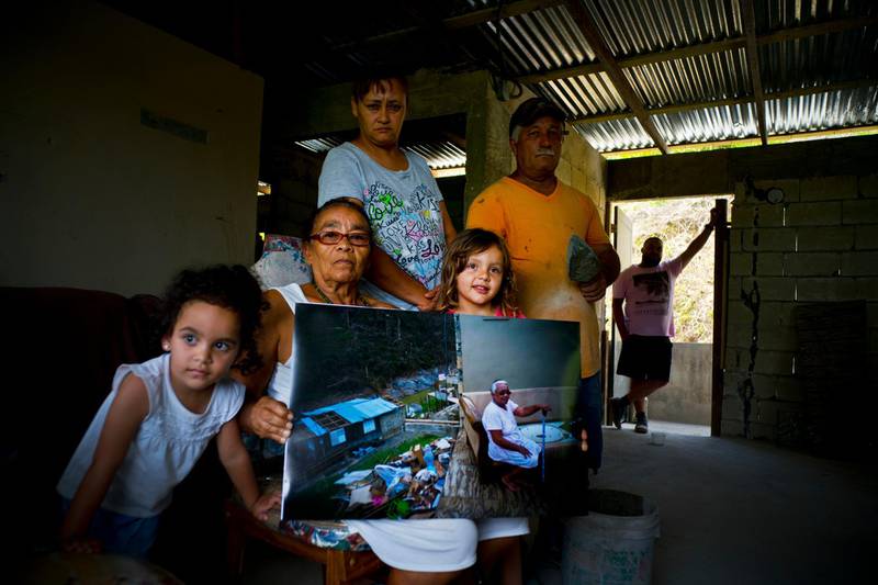 Juana Sostre Vazquez holds a printed photograph of her taken after Hurricane Maria destroyed her home. Last year's storm ripped Sostre's wooden home off its foundation in the central mountain highlands.