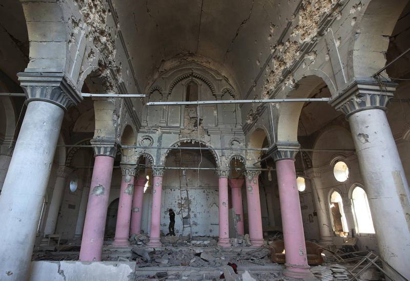 A Christian fighter from Hashed Al-Shaabi (Popular Moblisation units) wAlks inside a heavily damaged Syriac Orthodox church named Al-Tahira Al-Fawqaniya (The Immaculate) in the old city of Mosul on January 9, 2018. - Along the waterfront of the Tigris River in Iraq's war-torn Mosul, little is revealed but enormous heaps of rubble. Six months since Iraqi forces seized the country's second city from Islamic State group jihadists, human remains still rot in front of the Al-Nuri mosque. (Photo by AHMAD AL-RUBAYE / AFP)