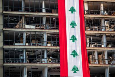 A banner with representations of the Lebanese flag hangs on a damaged building in a neighborhood near the site of last week's explosion that hit the seaport of Beirut, Lebanon, Wednesday, Aug. 12, 2020. (AP Photo/Hassan Ammar)