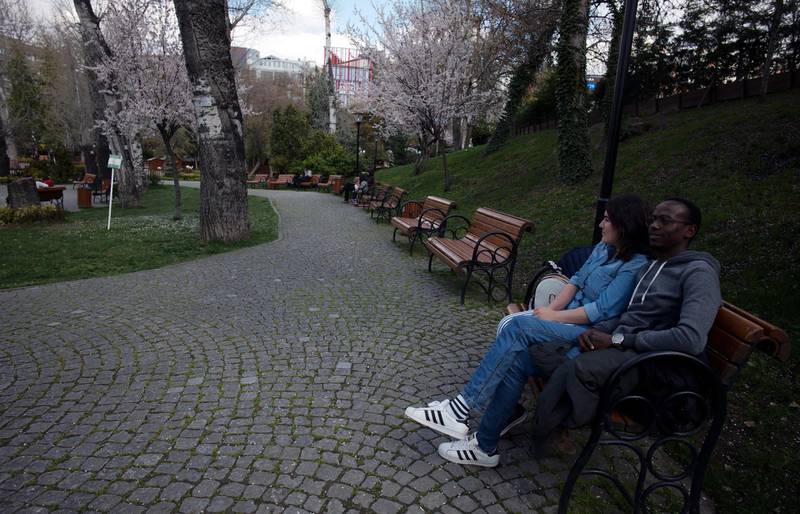A young couple sit together in a public garden despite a government call to 'stay at home' amid the coronavirus outbreak, in Ankara, Turkey. AP