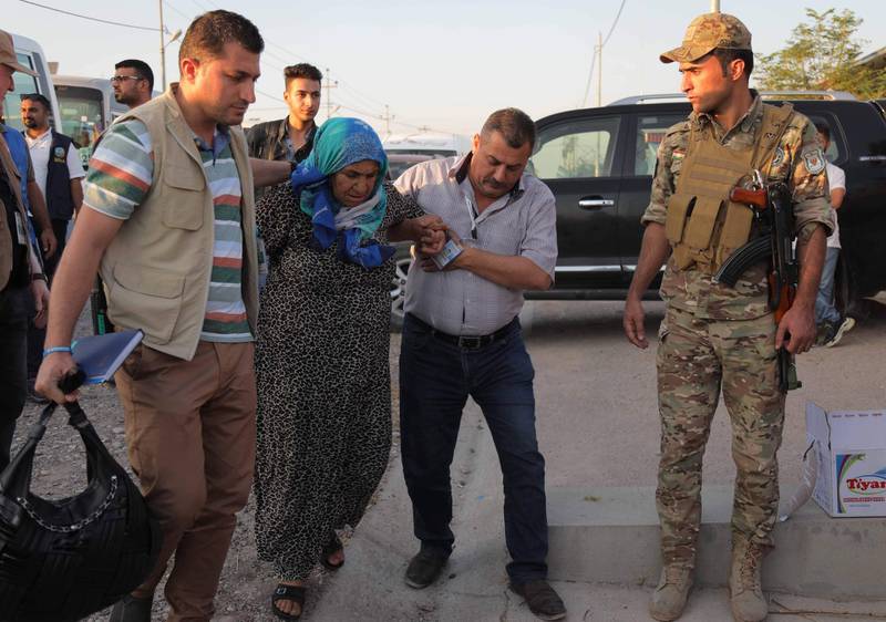 Men help an elderly woman after disembarking from a minibus transporting Syrians who have been recently-turned refugees by the Turkish military operation in northeastern Syria upon arriving at the Bardarash camp, near the Kurdish city of Dohuk, in Iraq's autonomous Kurdish region, on October 16, 2019. Some 500 Syrian Kurds have entered neighbouring Iraqi Kurdistan over the past four days fleeing a Turkish invasion now entering its second week, officials said. Iraqi Kurdistan previously hosted more than one million Iraqis who fled fighting with the jihadists of the Islamic State group between 2014 and 2017.
 / AFP / Safin HAMED
