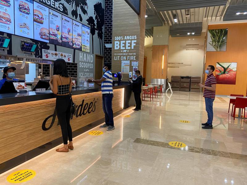 People wearing protective face masks order food as they keep social distancing at the food court in Dubai Mall. Reuters