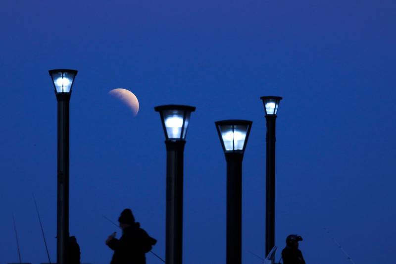 Men stand below street lights as the moon rises during a partial lunar eclipse in Buenos Aires, Argentina. AP Photo/Natacha Pisarenko