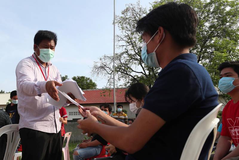 A medical officer, left, gives a form to villagers before they get their second dose of Sinopharm Covid-19 vaccines, outside Phnom Penh, Cambodia. AP Photo