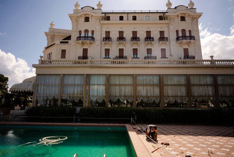 A man does maintenance work by a swimming pool of the Rimini Grand Hotel, in Rimini, Italy. The seaside resort is gearing up to welcome tourists again. AP Photo/Domenico Stinellis