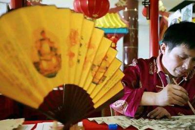 Businesses are going into high gear for the Chinese New Year next week. Above, an entrepreneur at Dragon Mart paints a handmade Chinese fan, considered as a good luck charm and expression of generosity. Pawan Singh / The National