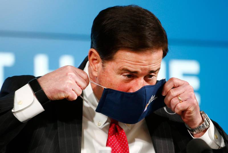 Gov Doug Ducey places his face mask back on before leaving a press conference on Covid-19 in the state at the Arizona Commerce Authority Conference Center in Phoenix, Arizona, USA. The Arizona Republic via AP