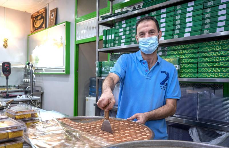 Abu Dhabi, United Arab Emirates, October  12, 2020.  Khalidiya by night article by Saeed Saeed on restaurants, café's on Al Yahar Street.  Mohammed Al Ayoubi cuts authentic Lebanese Harissa from Tripoli Sweets.
Victor Besa/The National
Section:  NA
Reporter:  Saeed Saeed