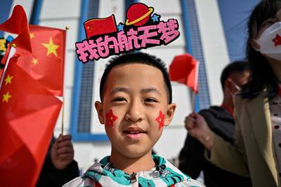 A boy waves Chinese flags while waiting for the launch at the centre in Gansu province. AFP