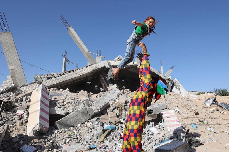 A Palestinian man plays with a child among the ruins of a building destroyed during recent Israeli bombing in Rafah, in the southern Gaza Strip.  AFP
