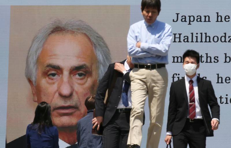 Pedestrians walk past a huge monitor showing a news photo of Japanese men's national soccer coach Vahid Halilhodzic in Tokyo, Monday, April 9, 2018. Halilhodzic has reportedly been dismissed as Japan's head coach following two disappointing international friendly matches and with the World Cup opening in just over two months. (AP Photo/Koji Sasahara)