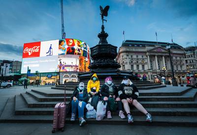Four women wearing face masks sit on the steps of the Eros statue in Piccadilly Circus in London, Britain.  EPA