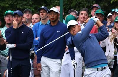 Tom Kim hits his tee shot on the 14th during a practice round as Rory McIlroy and Tiger Woods look on. Reuters
