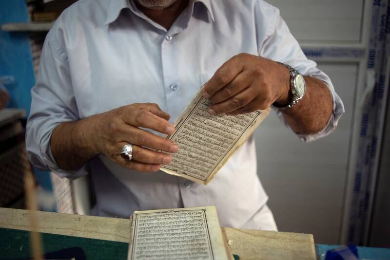 An artisan glues the pages of an old Quran in Tripoli. Reuters