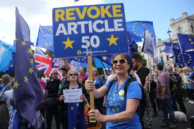 Anti-Brexit demonstrators hold up placards as they march outside the Houses of Parliament in central London. AFP