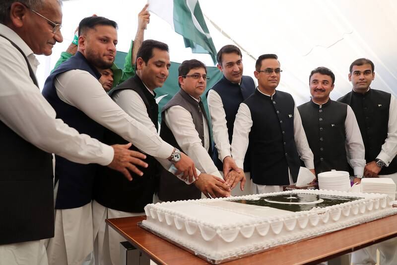 Mr Khan, centre, is joined by other officials to cut a cake as part of the Independence Day celebrations.