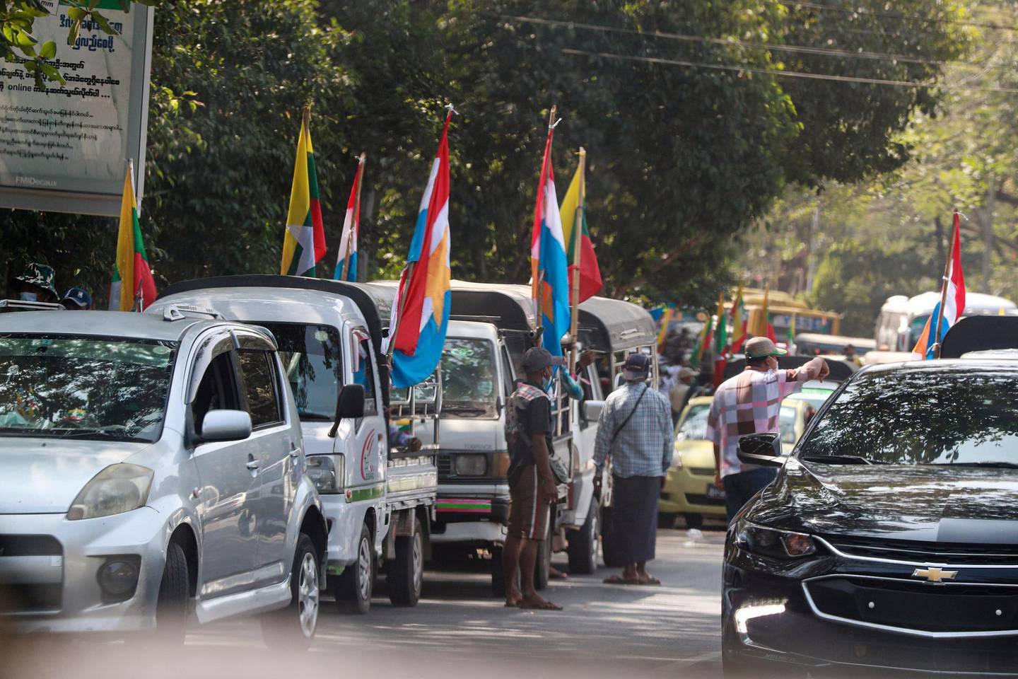 Supporters of the Myanmar military gather near trucks adorned with the military flag, Buddhist religious flag and national flag Monday, Feb. 1, 2021, in Yangon, Myanmar. Myanmar military television said Monday that the military was taking control of the country for one year, while reports said many of the country's senior politicians including Aung San Suu Kyi had been detained. (AP Photo/Thein Zaw)