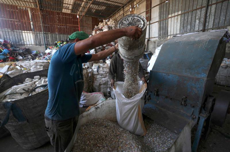A worker pours shredded plastic into a furnace.

