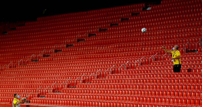 A staff member retrieves the ball from the empty stands. Reuters