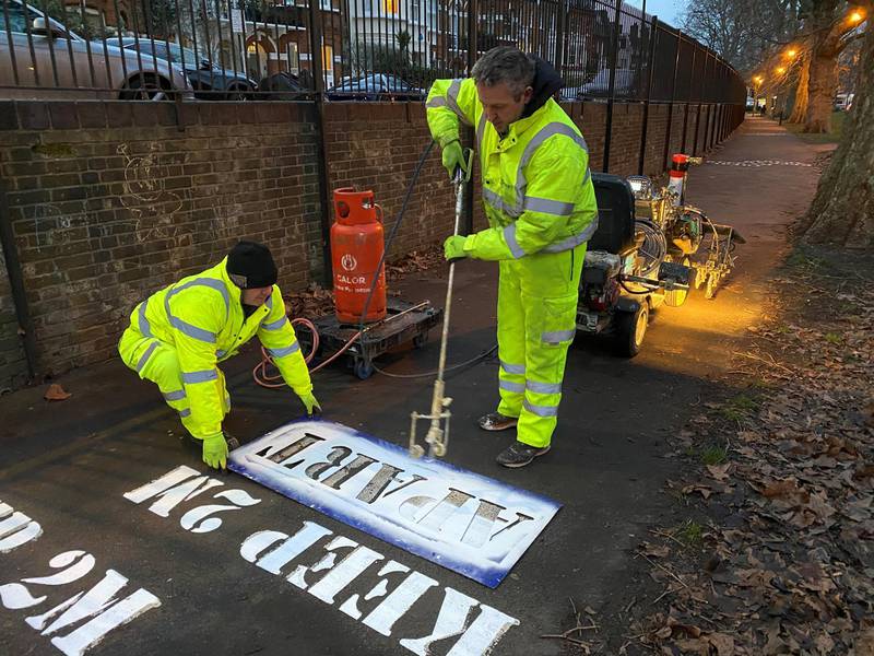 Workers paint social distancing signs at Eel Brook Common in Fulham, London. Reuters