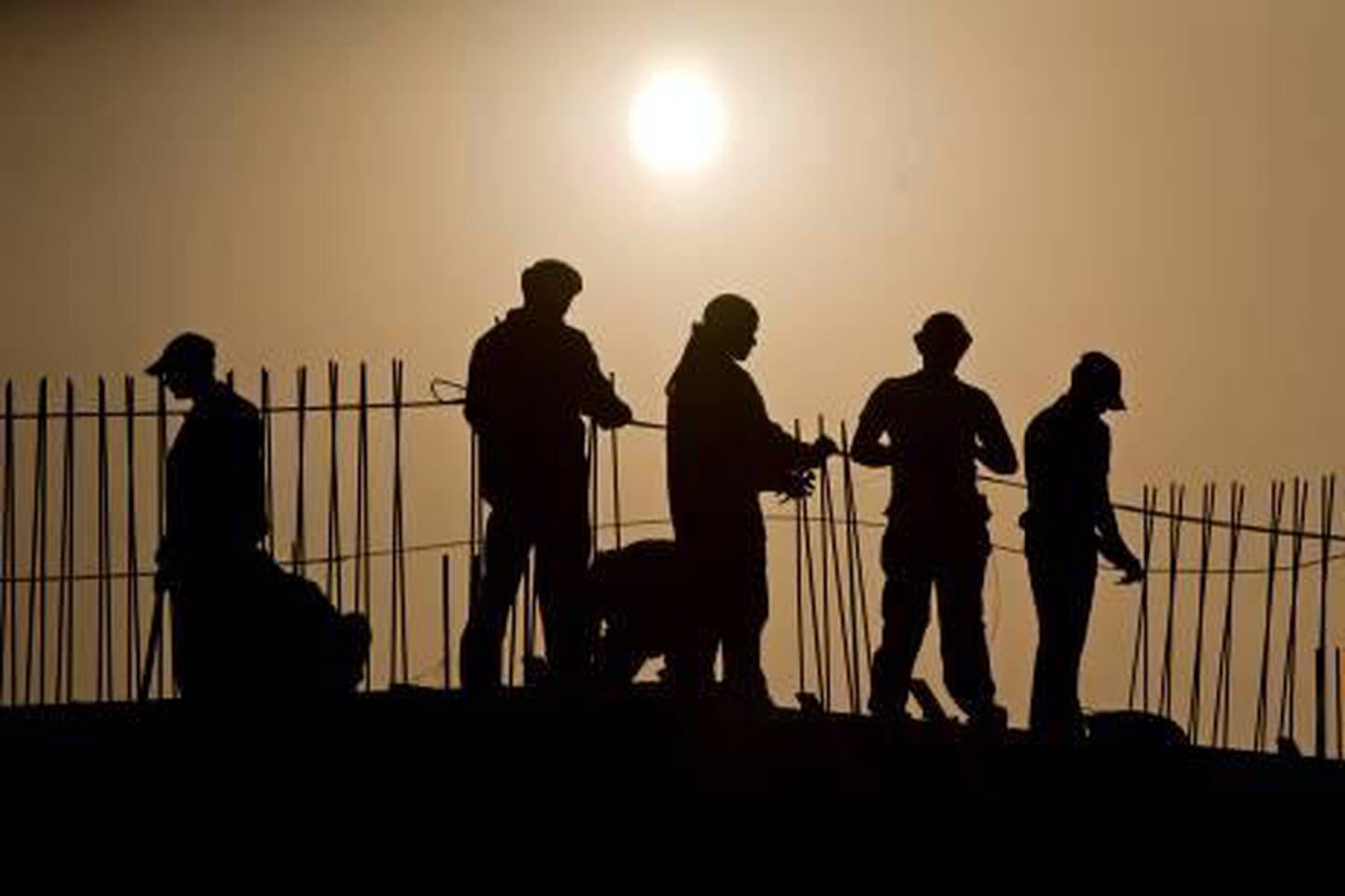 Ras al Khaimah - September 8, 2009 - Construction continues on a retail shopping building as workers secure rebar on the project in Al Hamra Marina near Ras al Khaimah September 8, 2009. (Photo by Jeff Topping/The National)  *** Local Caption ***  JT003-0908-RAK SUNSET WORKERS_MG_1442.jpg