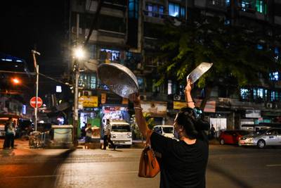 A woman clatters pans to make noise after calls for protest went out on social media in Yangon. AFP