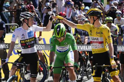 Tadej Pogacar, wearing the overall leader's yellow jersey, greets Denmark's Jonas Vingegaard, wearing the best young rider's white jersey.