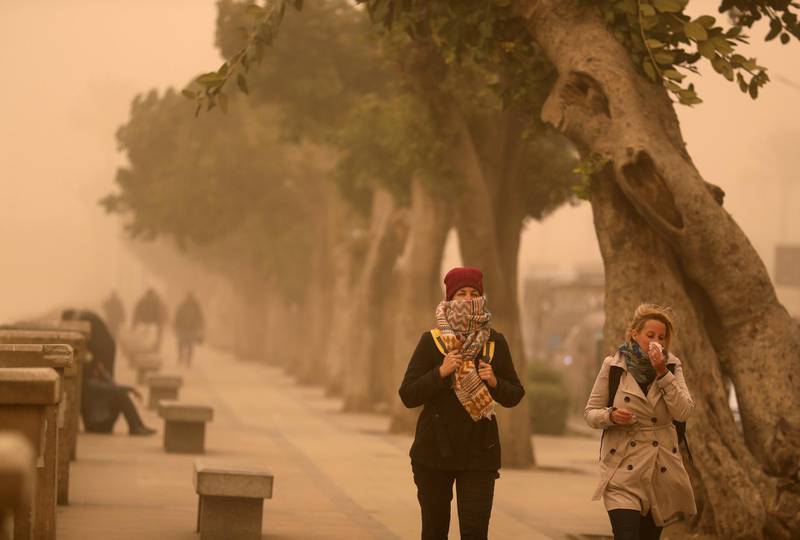Women cover their face near the River Nile during a sandstorm in Cairo. Reuters