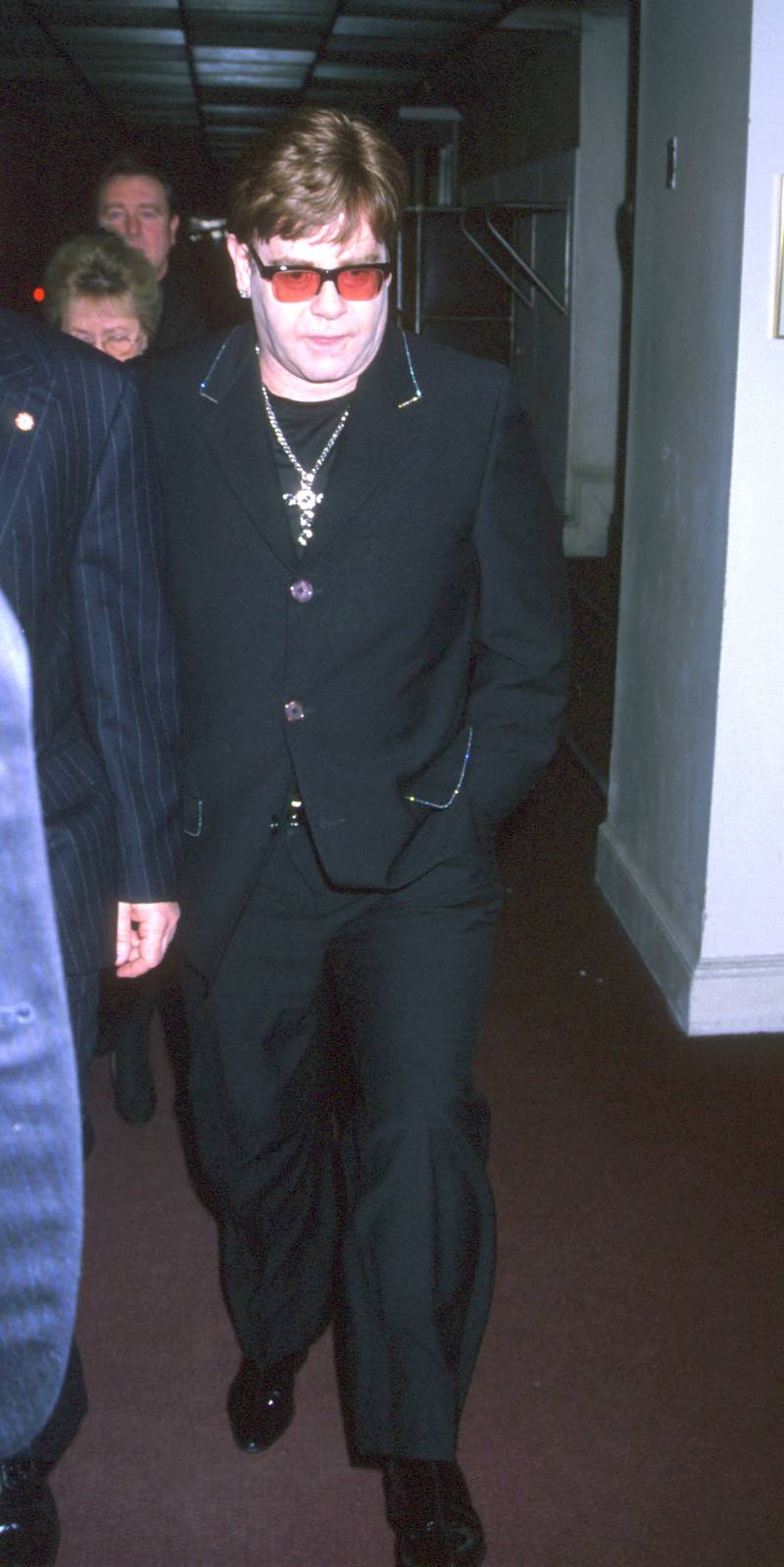 Elton John, wearing a black suit with sparkling detailing and a silver cross, leaves a New York City concert on July 27, 1999.  Getty Images