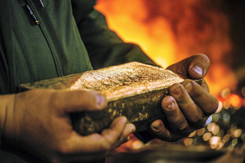 A worker carries a 28 kilogram gold bar after casting and cleaning in the foundry at a gold mine in Westonaria, South Africa. Photographer: Waldo Swiegers/Bloomberg