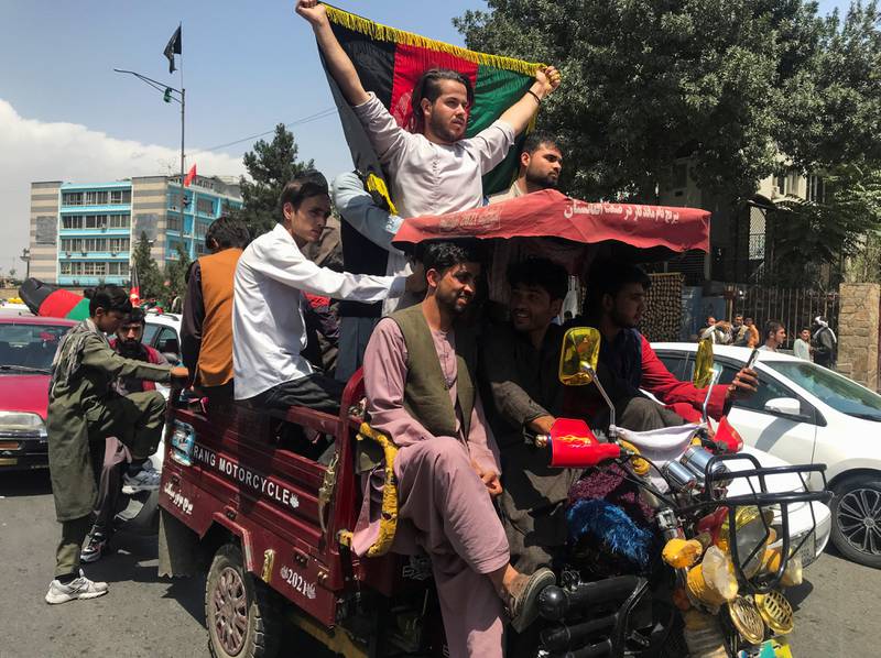 A procession of cars and people carrying Afghan flags makes its way through the streets.  Reuters