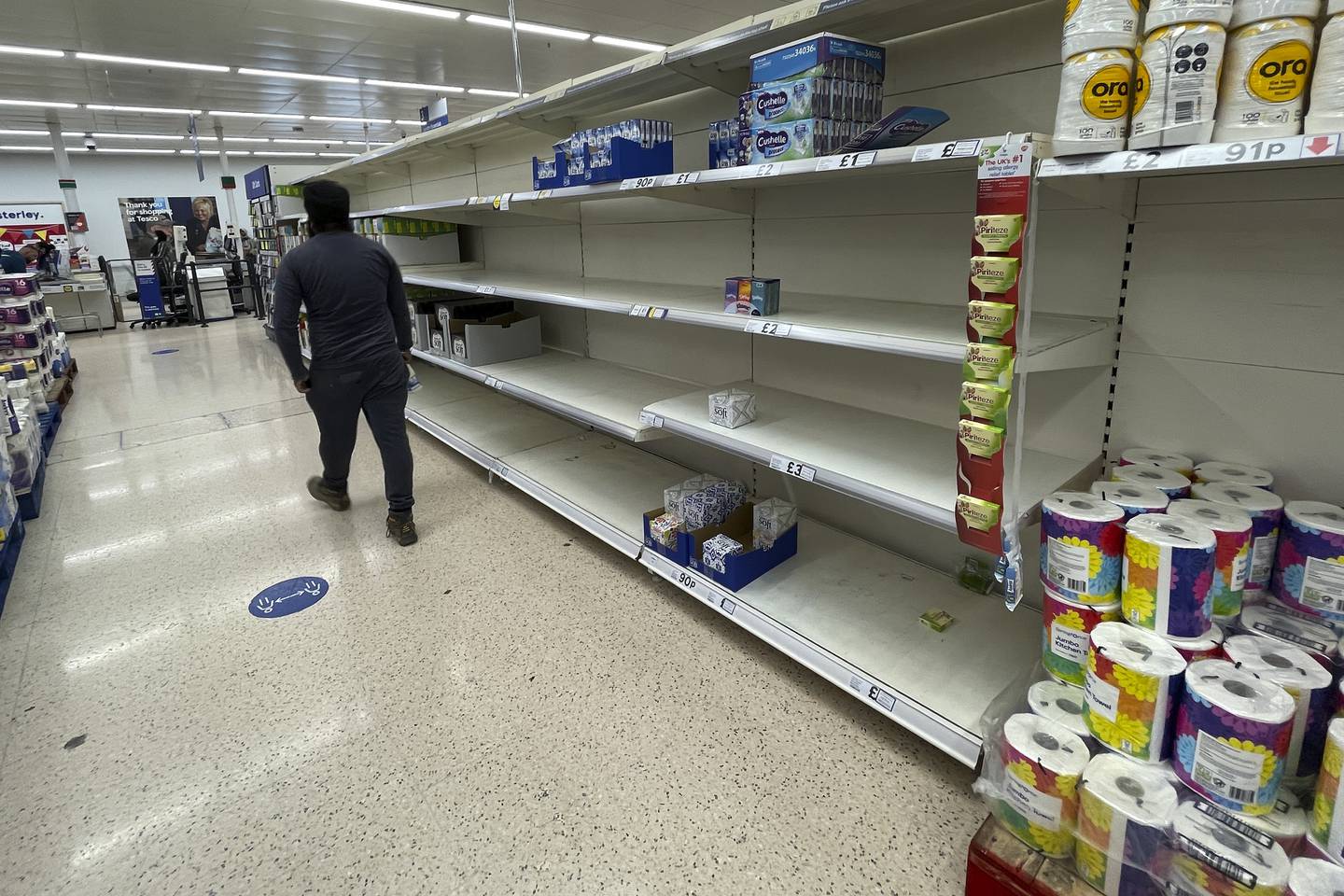 A shopper walks past empty shelves at a supermarket in London. AP
