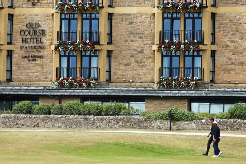 Adrian Meronk and Tiger Woods  make their way past the Old Course Hotel. Getty