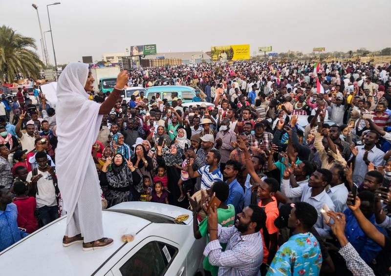 Alaa Salah, a Sudanese woman propelled to internet fame earlier this week after clips went viral of her leading powerful protest chants against President Omar al-Bashir, addresses protesters during a demonstration in front of the military headquarters in the capital Khartoum on April 10, 2019. - In the clips and photos, the elegant Salah stands atop a car wearing a long white headscarf and skirt as she sings and works the crowd, her golden full-moon earings reflecting light from the fading sunset and a sea of camera phones surrounding her. Dubbed online as "Kandaka", or Nubian queen, she has become a symbol of the protests which she says have traditionally had a female backbone in Sudan. (Photo by - / AFP)