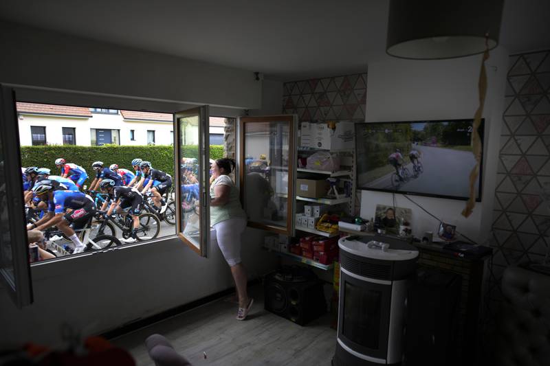 A woman cheers the riders from inside her home on Stage 4. AP
