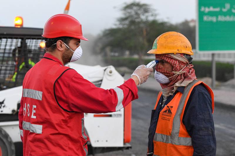 epa08330705 A person checks temperature of workers before entering a worksite in Kuwait City, Kuwait, 29 March 2020. Kuwait imposed a nationwide curfew due to the ongoing pandemic of the Covid-19 disease caused by the SARS-CoV-2 coronavirus.  EPA/NOUFAL IBRAHIM