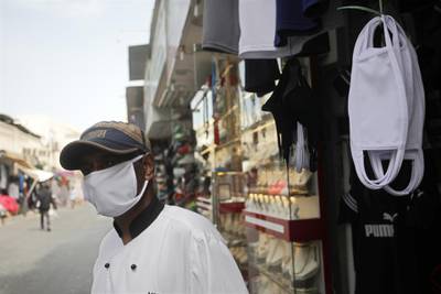 epa08310102 A man wearing a protective face mask stands next to a stall selling masks in a street of Manama, Bahrain, 20 March 2020. According to media sources, Bahrain on 19 March 2020 reported some 269 cases that tested positive to the COVID-19 coronavirus disease. All types of education facilities, gyms, cinemas, and restaurants were closed amid the coronavirus COVID-19 pandemic.  EPA/AHMED ALFARADAN