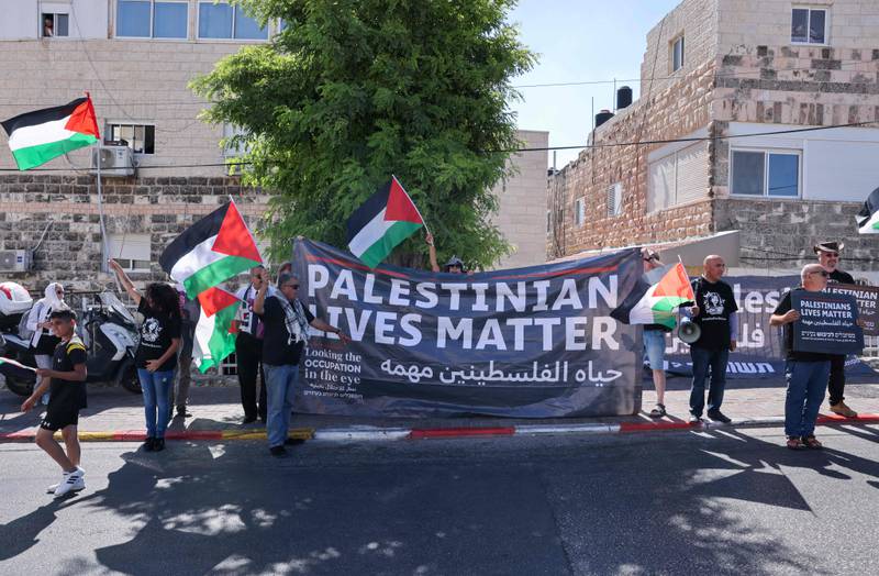 Palestinian and Israeli human rights campaigners lift banners during a rally near Augusta Victoria Hospital in East Jerusalem as US President Joe Binden visits. AFP