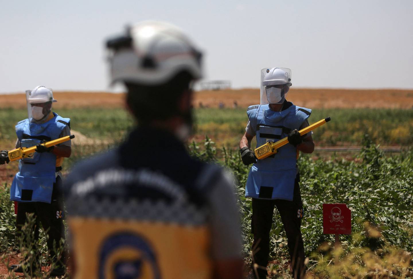 Members of White Helmets, equipped with protective outfits, get ready to search and neutralise unexploded weapons in a field in Syria's northern Aleppo province in June. AFP