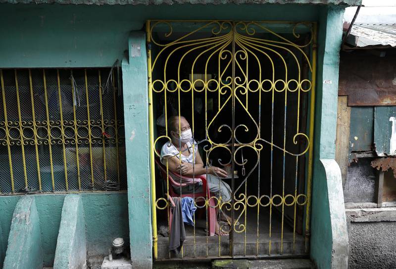 A resident sits inside her home in the city of Navotas, Manila, before a lockdown to contain the coronavirus pandemic in the Philippines got under way. The infections continue to rise in the country after reopening the economy suffering a twin blow of recession and the pandemic. AP Photo