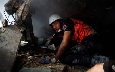 A rescue worker searches for casualties under the rubble of a building in Khan Younis. Reuters